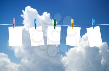 Blank photos hanging on a clothesline, blue sky on background