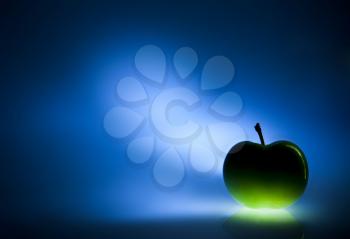 Green apple on blue mysterious defocus background,  space for text