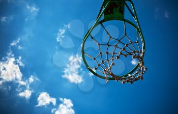 Old basketball basket with a cloudy blue sky in the background. 