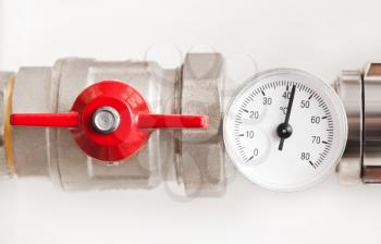 Water thermometer with red valve and metal pipes 