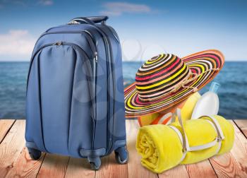 Blue travel bag and beach items, blur sea on background, template design