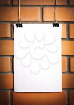 Blank white poster on a rope, brick wall on the background