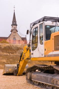 An orange bulldozer in front of a church