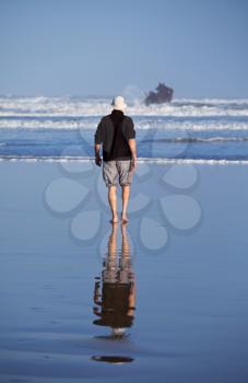 Royalty Free Photo of a Man Walking on a Beach in Morocco Near a Shipwreck