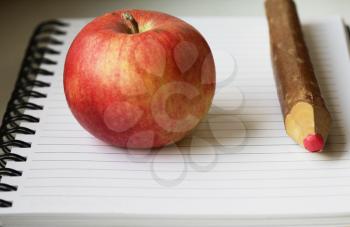 Royalty Free Photo of an Apple and Pencil on a Pad of Paper