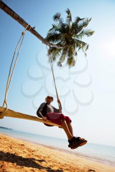 Royalty Free Photo of a Boy Sitting on a Swing at a Beach