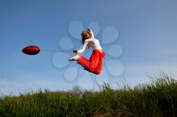 Royalty Free Photo of a Woman Jumping and Holding a Balloon