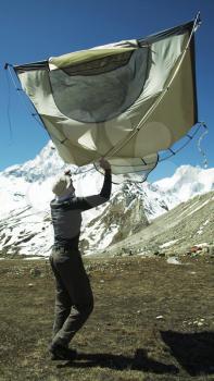 Royalty Free Photo of a Climber Setting Up a Tent with Shivling Peak in the Background