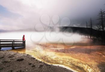 Royalty Free Photo of a Man Standing on a Boardwalk Looking at a Hot Spring