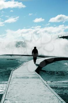 Royalty Free Photo of a Man Walking on a Boardwalk at a Hot Spring