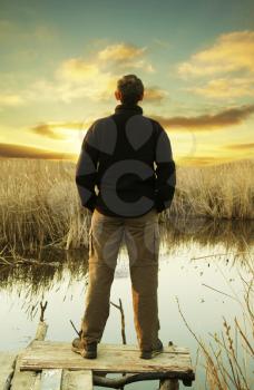 Royalty Free Photo of a Man Looking Out on a Lake at Sunset