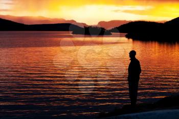 Royalty Free Photo of a Silhouette of a Man Standing Beside a Lake