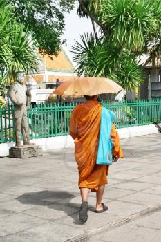 Royalty Free Photo of a Monk Walking Under an Umbrella
