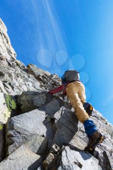 Climber scrambling up by rocky terrain