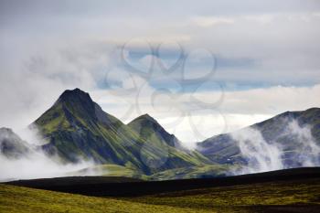 Beautiful Icelandic landscape. Green volcanic mountains in cloudy weather. 