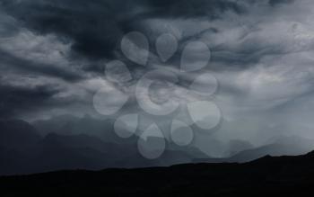 Summer rain in the mountains. Dramatic clouds and mountains silhouette.