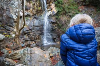 Little girl standing in front of waterfall.