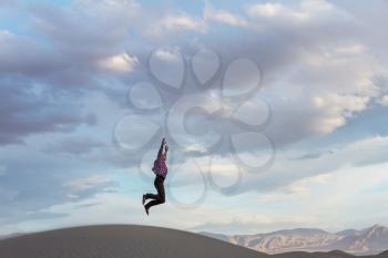 Jumping man in sand dunes at sunset