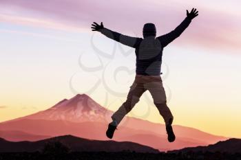 Jumping man in high mountains at sunset
