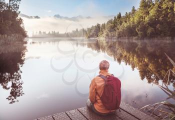 A man is sitting at ease by the calm lake. Relaxation vacation