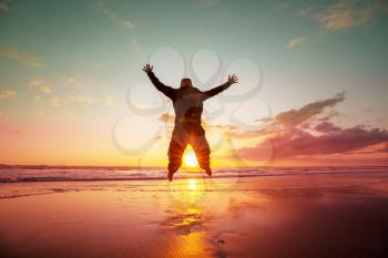 Jumping man on sunset beach