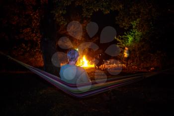 Amazing scene in night camping -man in hammock on bonfire background