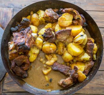 Beef meat stewed with potatoes on wooden background