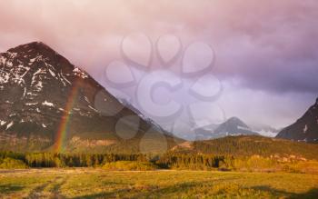 Rainbow above mountains. Beautiful natural landscapes. Picturesque rocky peaks of the Glacier National Park, Montana, USA