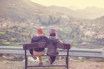 couple sitting on a wooden bench in mountains