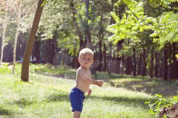 Little boy do his first steps  in summer park
