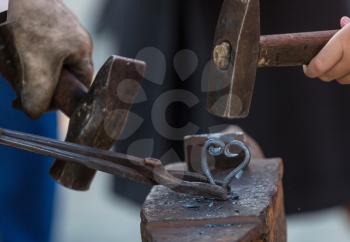The blacksmith manually forging the molten metal on anvil
