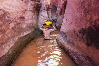 Hiker in slot canyon in Grand Staircase Escalante National park, Utah, USA. Unusual colorful sandstone formations in deserts of Utah are popular destination for hikers.
