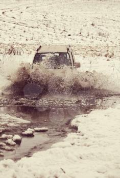 4x4 vehicles drive through the water splashing in winter season