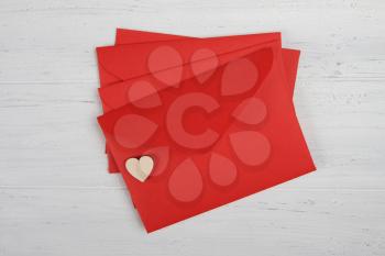 Red paper envelopes with hearts on white wooden background