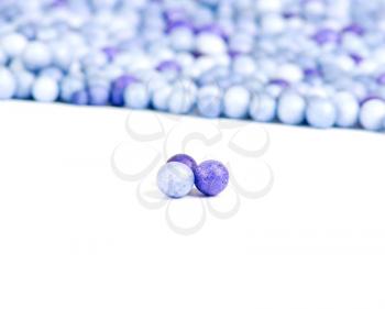 One blue and two violet little pearls isolated on background of other pearls.