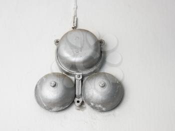 Big old silvery school bell, against a white wall