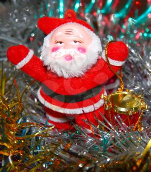 Doll of Santa Claus with a red drum against a tinsel