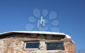 Aerial mobile communication on a roof of the old house against the blue sky