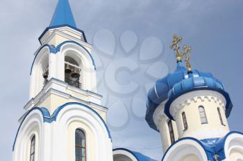 Church white with blue domes bells and gold crosses against the blue sky
