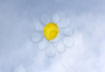 Yellow balloon flying on a blue sky background.