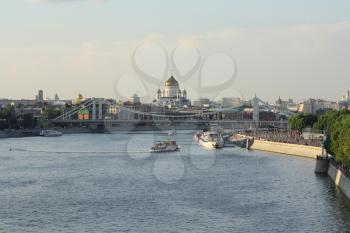 Moskva river with river buses from Novoandreevskiy Bridge. Krymsky bridge and Cathedral of Christ the Savior on the horizon in Moscow, Russia.