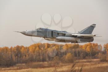 Military jet bomber Su-24 Fencer flying above ground.