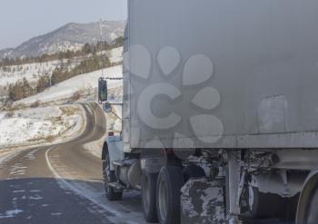 Speeding truck wheels on icy road during winter storm.