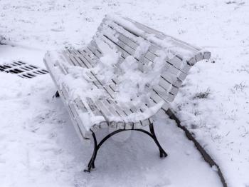 Bench in the park covered with snow.