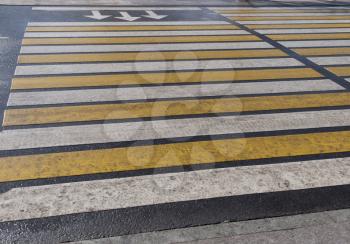Bright yellow and white stripes of zebra crossing, pedestrian crosswalk.