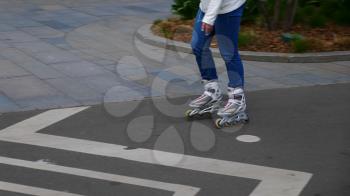 Feet of girl riding on a roller skates ride on asphalt.