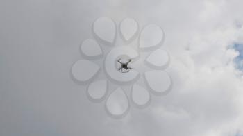Flying helicopter dron on a background of white clouds.