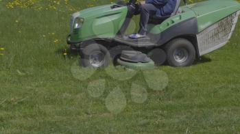 Worker mows green grass lawnmower on spring day