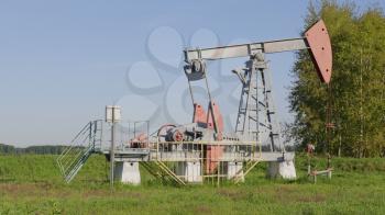 Operating oil and gas well in oil field, profiled against the blue sky.