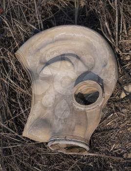 An old gas mask lies in a field on the ground.